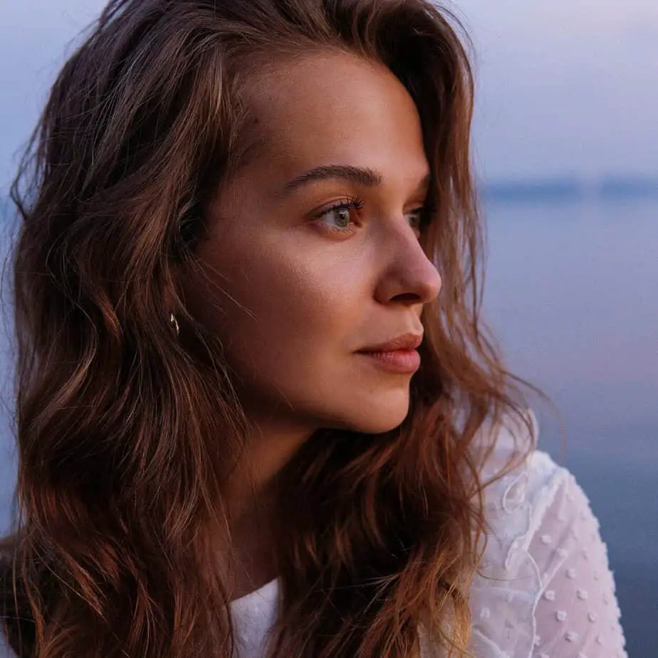 Portrait of brunette woman by the sea styling wavy hair